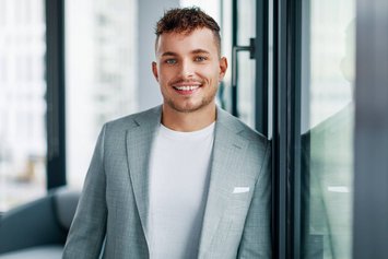 Mann mit grauem Anzug und weißem T-Shirt lächelnd