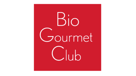 Ein rotes Quadrat zeigt den Text "Bio Gourmet Club" in weißer Schrift. Der Hintergrund ist einfarbig rot, während der Schriftstil elegant und modern erscheint.