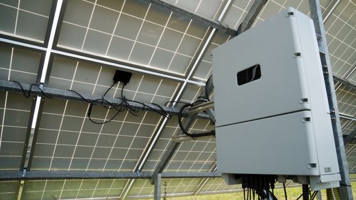 PV-Anlage von hinten aufgenommen. Darunter ist ein weißer Kasten angebracht und durch Kabel mit der PV-Anlage verbunden.