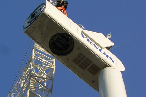 Foto von unten der Rotormontage auf der Welle einer Windkraftanlage mit einem weißen Kran.