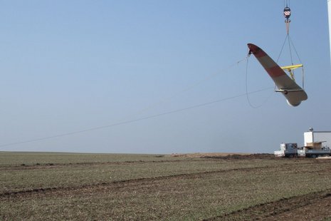 Ein Windradblatt wird über einem Feld in die Luft gehoben.